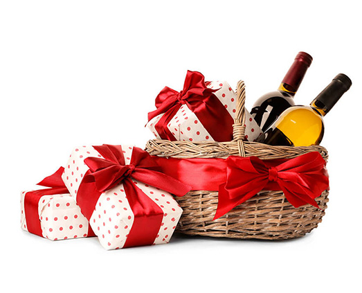 Gift basket with wine bottles and wrapped presents with red ribbons on white background.